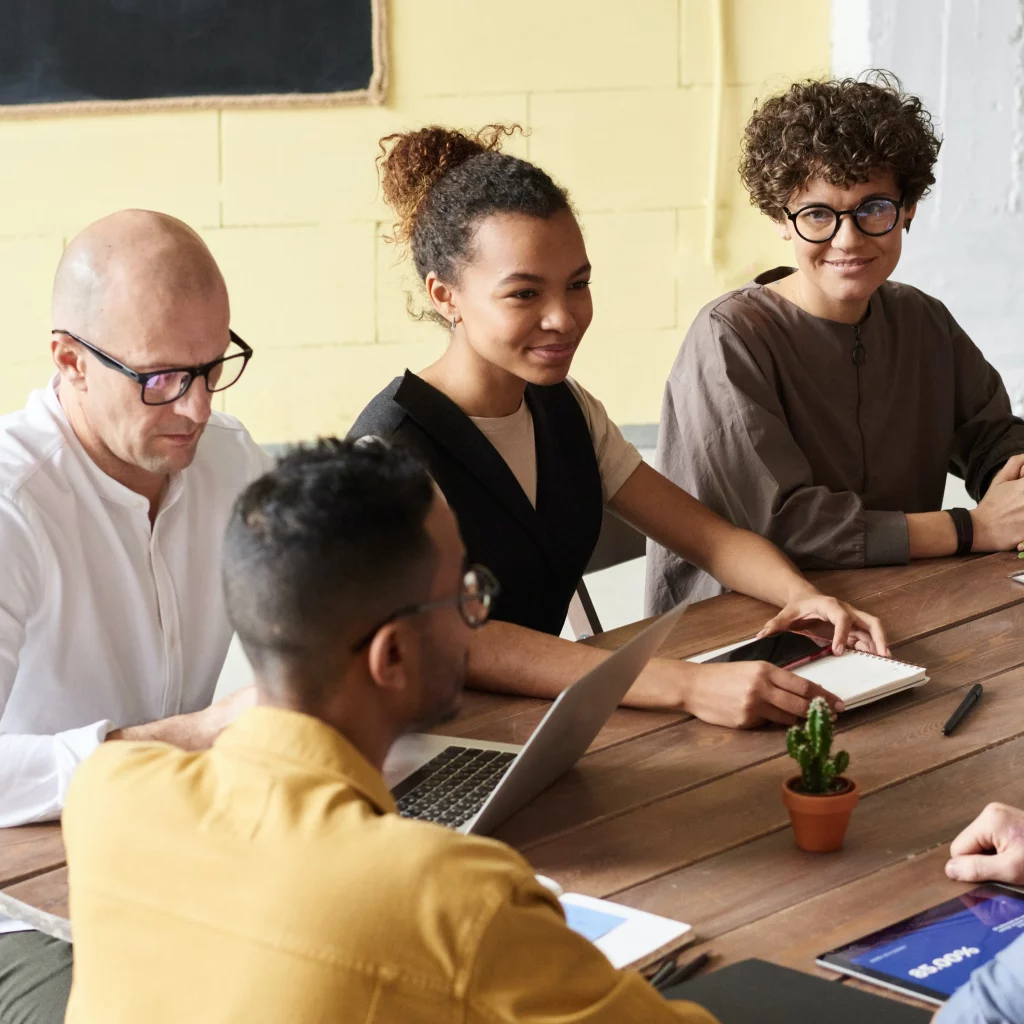 Photo of People Lying on a Wooden Table Discussing IT Staffing Solutions Free stock photo (pexels.com)