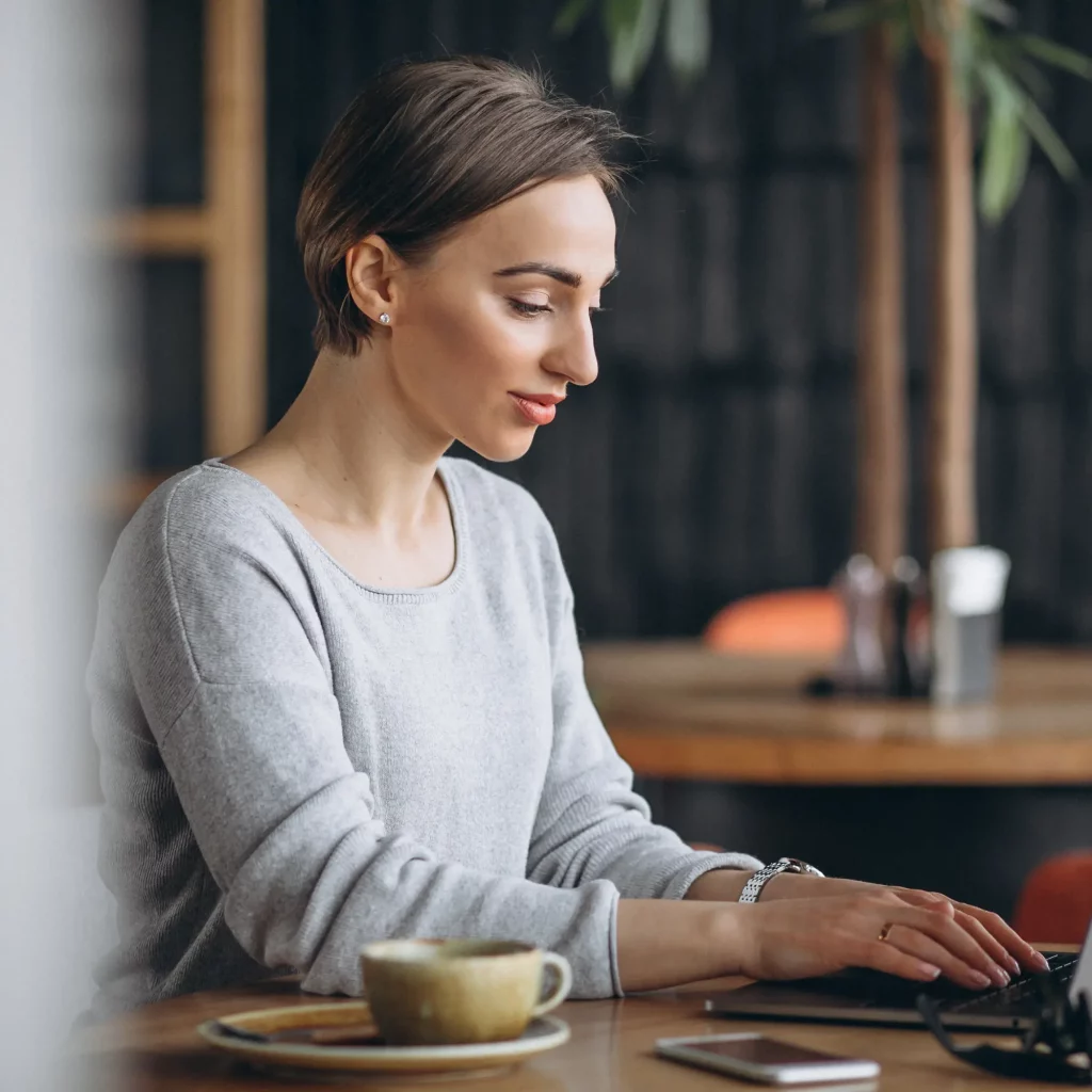 woman-sitting-cafe-drinking-coffee-working-computer